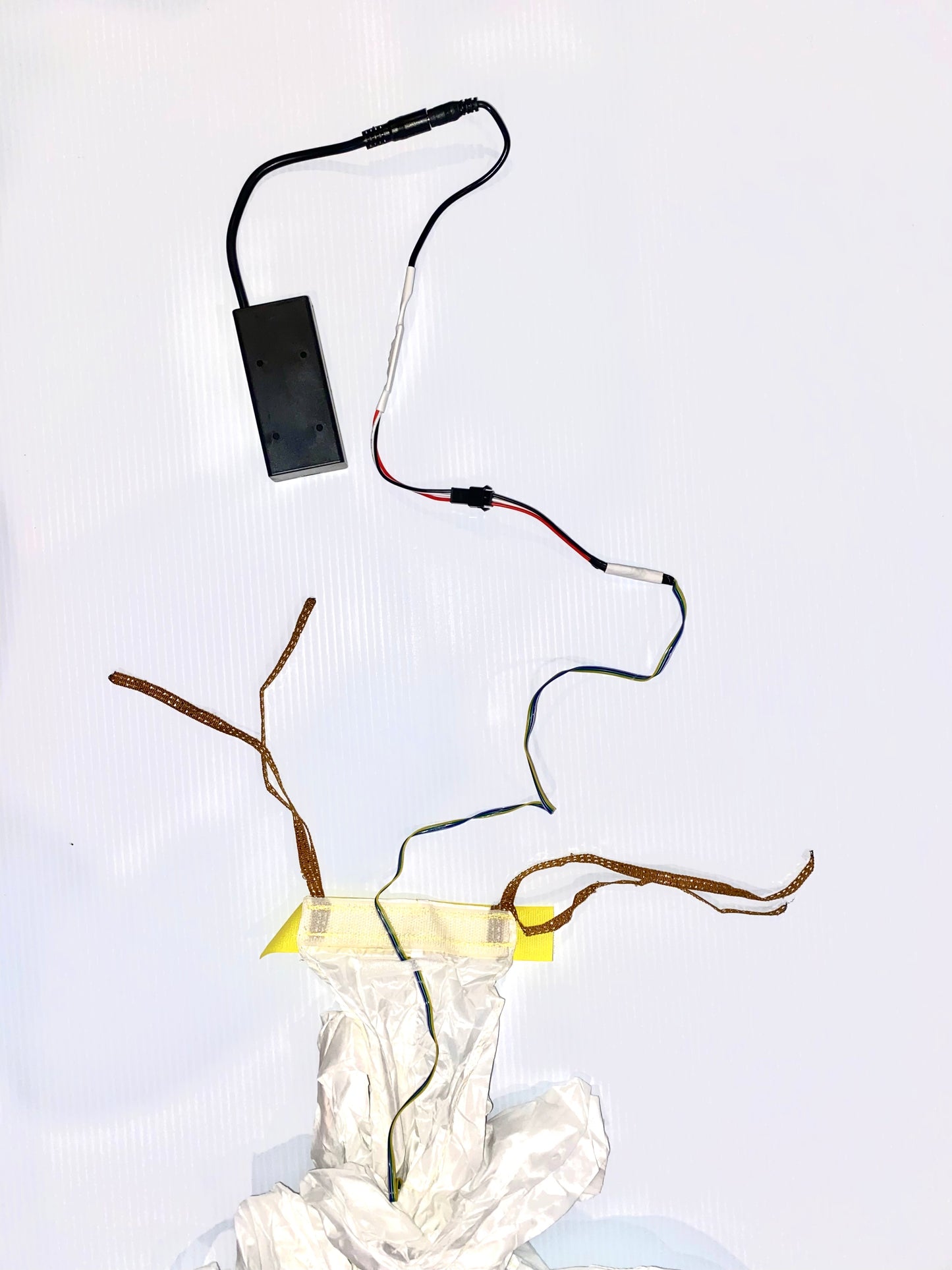 End of a tube tail that shows wiring and a battery box against a white background. 