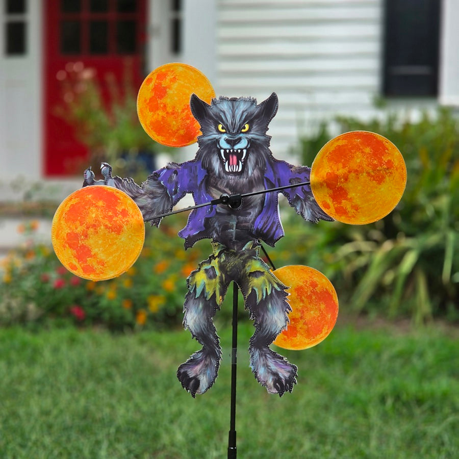 A Halloween yard decoration featuring a snarling werewolf with a purple jacket and four orange glowing moon balls on a black stake, set in a grassy yard with a house in the background.