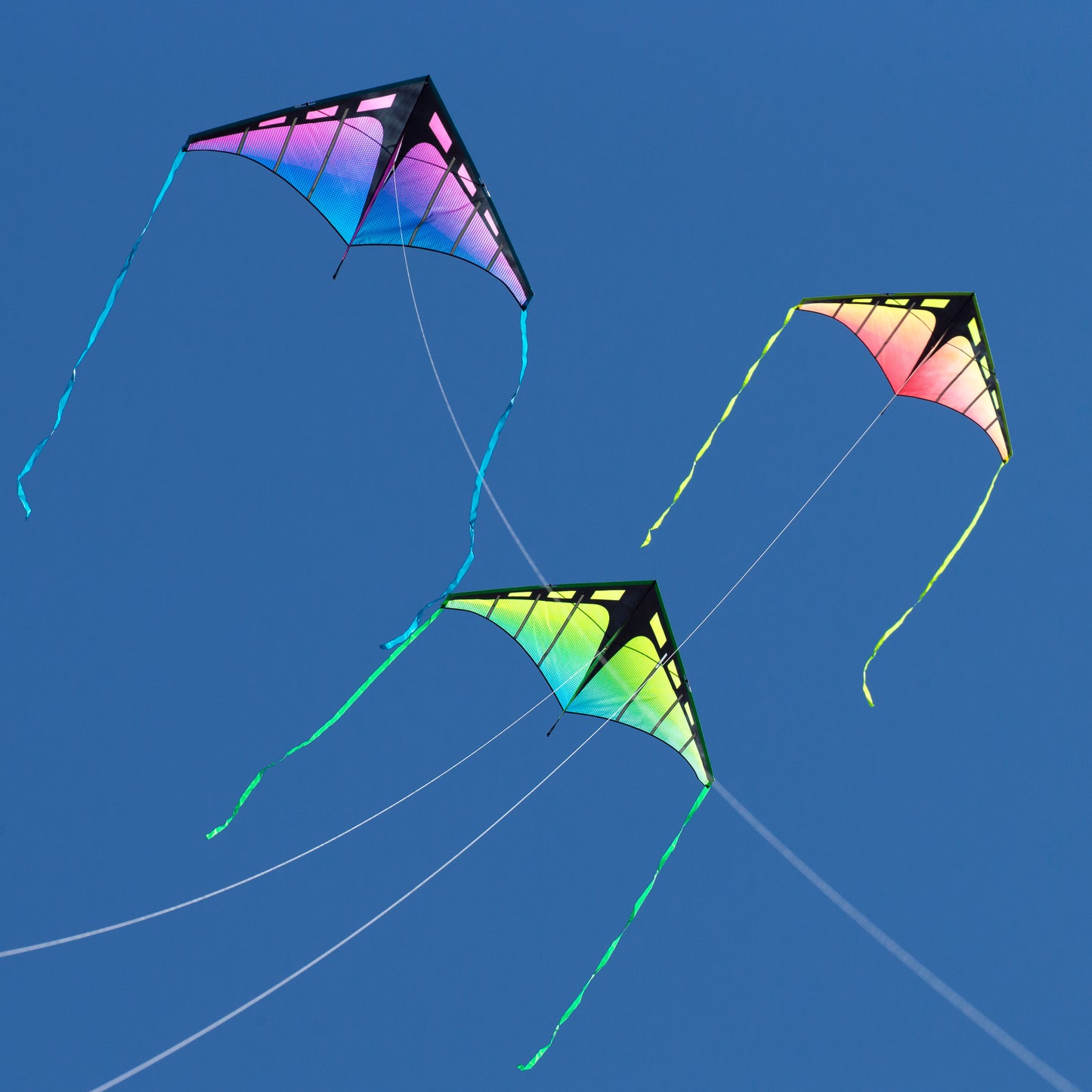 Three colorful kites flying against a clear blue sky.